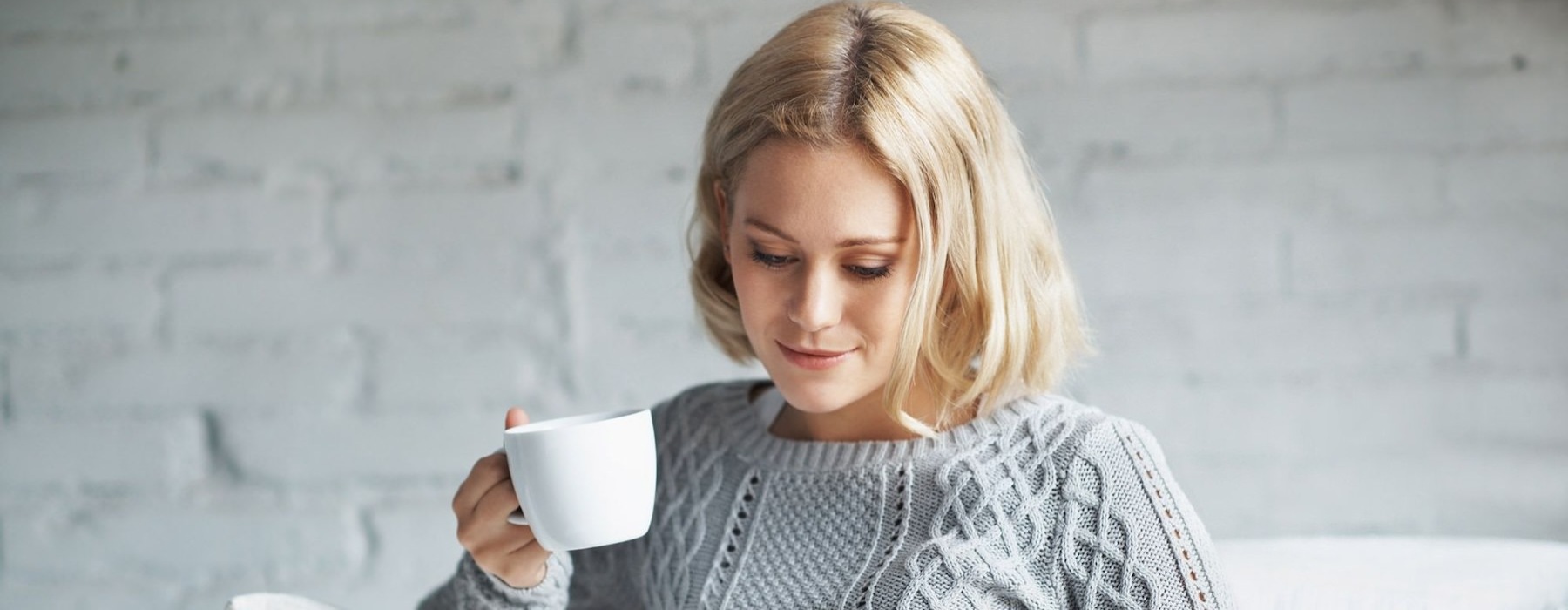 a woman holding a coffee cup looking at a tablet